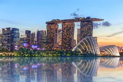 View of Marina Bay Sands and Supertree Grove at Gardens by the Bay, illuminated at night in Singapore’s futuristic skyline.